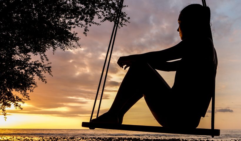 Una ragazza su un'altalena guarda l'orizzonte.